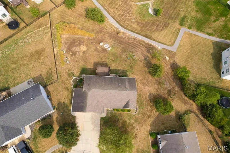 Aerial perspective of property featuring a neutral-toned shingle roof, paved driveway, and rear deck — 521 Cimarron Woods Court, Wentzville, MO 63385