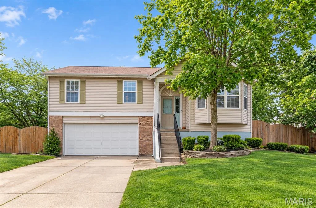 Two-story exterior with siding and brick accents, an attached garage, bay window, and mature landscaping — 105 Christina Marie Drive, O'Fallon, MO 63368
