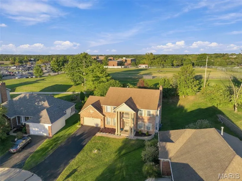 Two-story brick Grand Estate w/ a two-car garage, and Parkway West High in the background — 14901 Jockey Club Drive, Chesterfield, MO 63017