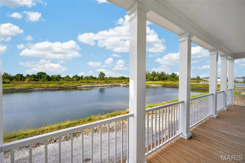 Expansive porch with wood-finish flooring, white balusters, and white columns — 2974 Memphis Street, St Charles, MO 63301