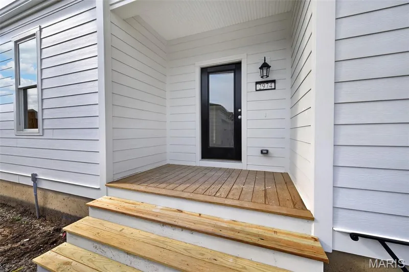Covered porch entry featuring wood plank flooring and wood steps — 2974 Memphis Street, St Charles, MO 63301