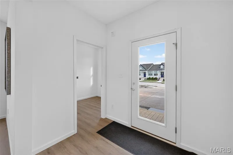 Entryway featuring a white door with a full-length glass insert, wood-finish flooring, and white walls — 2974 Memphis Street, St Charles, MO 63301