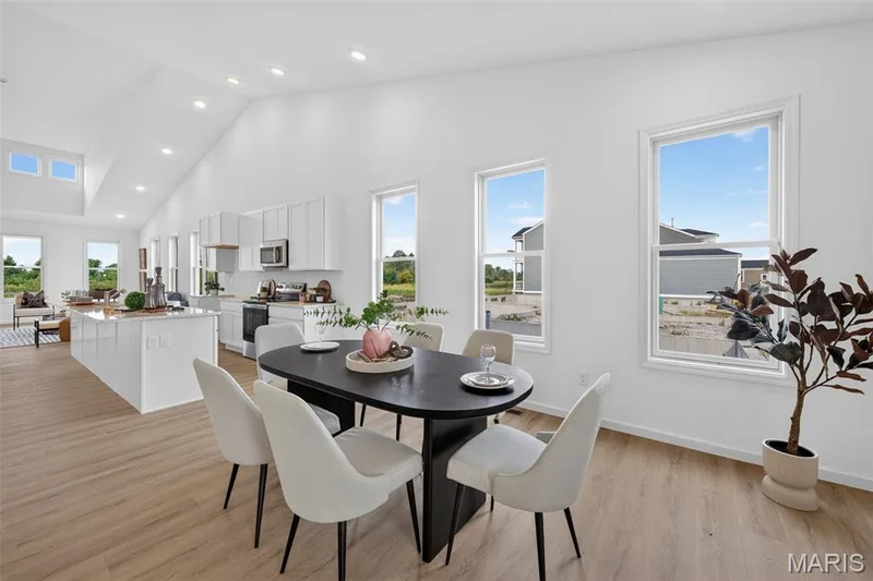 Vaulted ceiling with recessed lighting, LVP  flooring, white cabinetry, kitchen island, and multiple windows — 2974 Memphis Street, St Charles, MO 63301