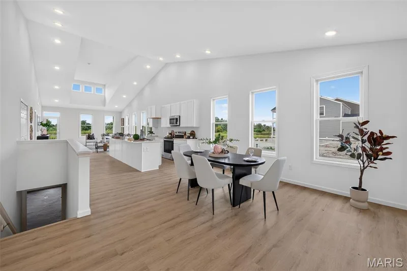 Open-concept living space featuring LVP flooring, a vaulted ceiling with recessed lighting, and multiple windows — 2974 Memphis Street, St Charles, MO 63301