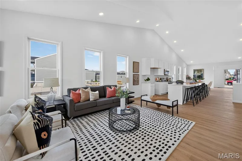 Vaulted ceilings, recessed lighting, LVP flooring, white cabinetry, and a kitchen island with seating — 2974 Memphis Street, St Charles, MO 63301