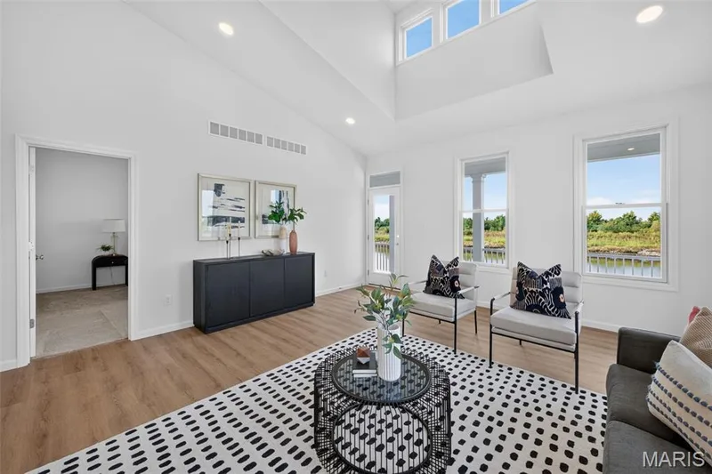 Vaulted ceiling, recessed lighting, LVP flooring, white walls, and a built-in black console cabinet — 2974 Memphis Street, St Charles, MO 63301