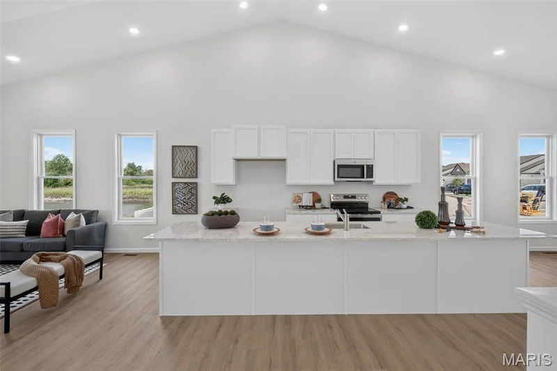 Vaulted ceiling, recessed LVP flooring, white cabinetry, and stainless steel appliances — 2974 Memphis Street, St Charles, MO 63301