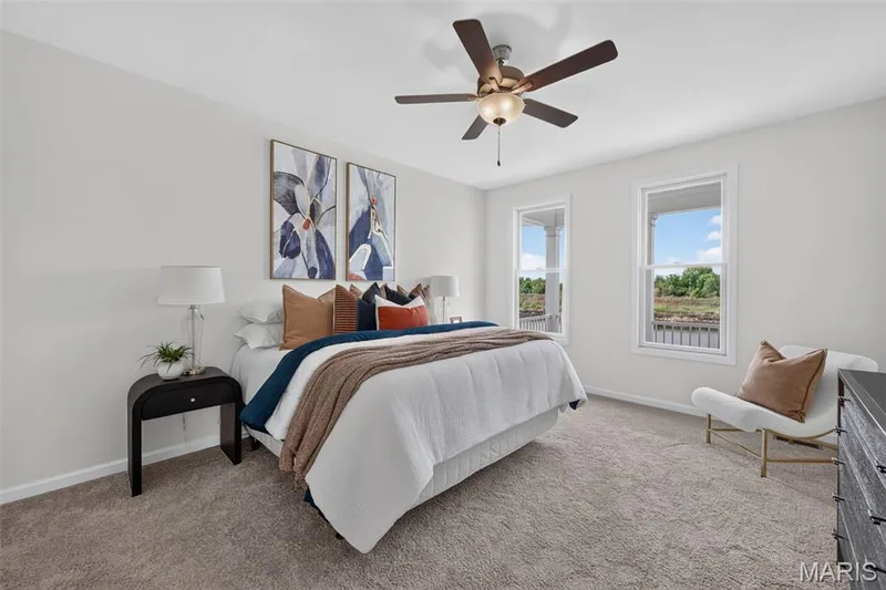 Light-colored wall finishes, carpeted flooring, two tall windows with white frames, and a ceiling fan with integrated lighting — 2974 Memphis Street, St Charles, MO 63301