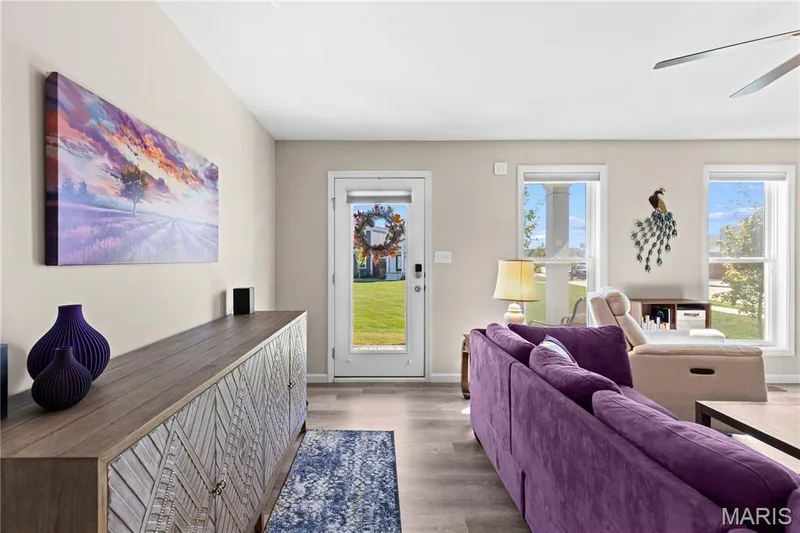 Luxury vinyl plank flooring, light neutral wall color, white trim, ceiling fan, and community green space access through a glass-paneled door — 200 Tiber Way, St Charles, MO 63301