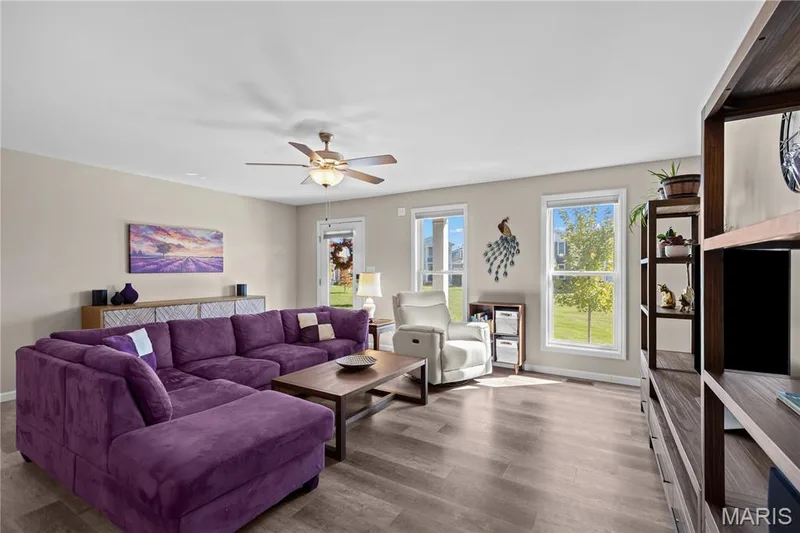 Spacious living area featuring luxury vinyl plank flooring, multiple windows, and a ceiling fan with integrated lighting — 200 Tiber Way, St Charles, MO 63301
