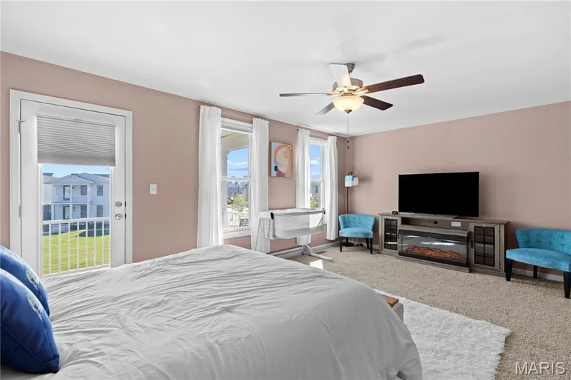 Carpeted flooring, ceiling fan with light fixture, multiple windows, and a glass-paneled door with white baluster railing — 200 Tiber Way, St Charles, MO 63301
