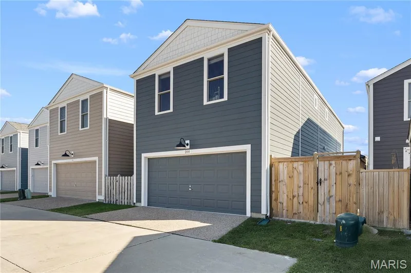 Modern exterior featuring blue-gray siding, white trim, a gabled roof, and a two-car garage — 200 Tiber Way, St Charles, MO 63301