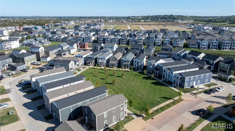 Expansive green spaces and trees complement a collection of multi-story homes with varied exterior finishes and multiple window styles — 200 Tiber Way, St Charles, MO 63301