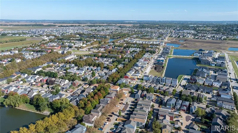 Expansive aerial perspective showcasing a residential community with mature landscaping, multiple bodies of water, and a mix of single-family residences and townhomes — 200 Tiber Way, St Charles, MO 63301