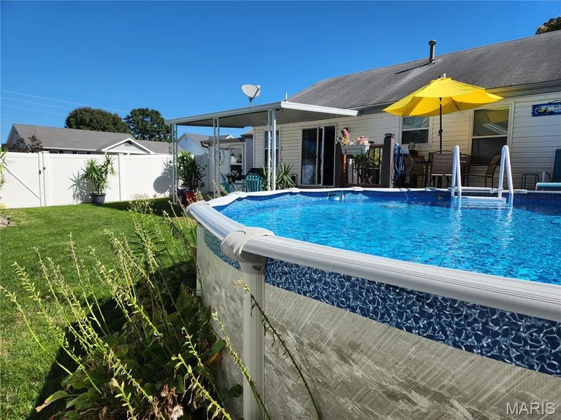 Above-ground pool with blue patterned liner, adjacent to a wooden deck with a sliding glass door, under a covered patio structure — 101 Eric Craig Court, St Peters, MO 63376