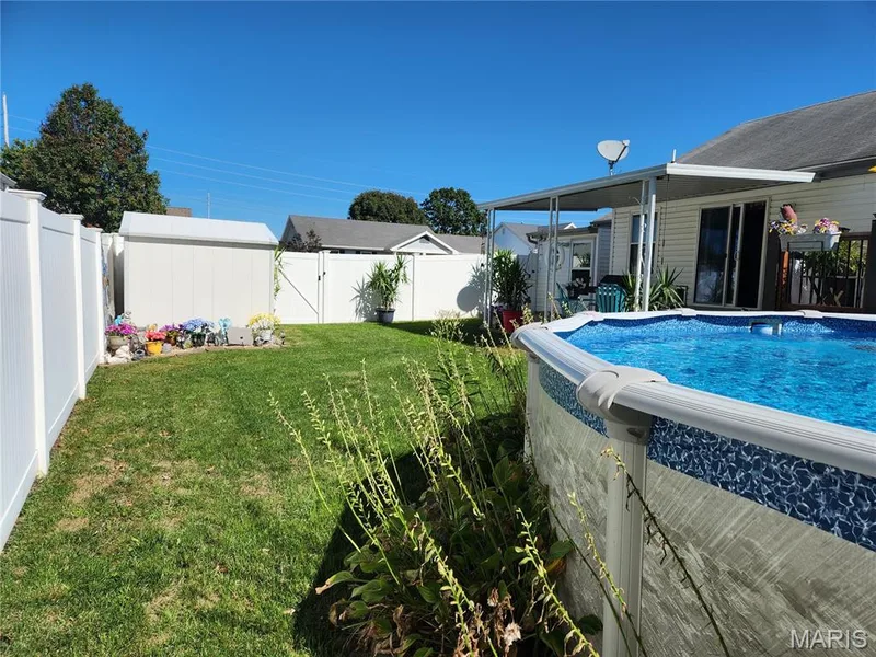Fenced backyard featuring a manicured lawn, above-ground pool, covered patio, and storage shed — 101 Eric Craig Court, St Peters, MO 63376