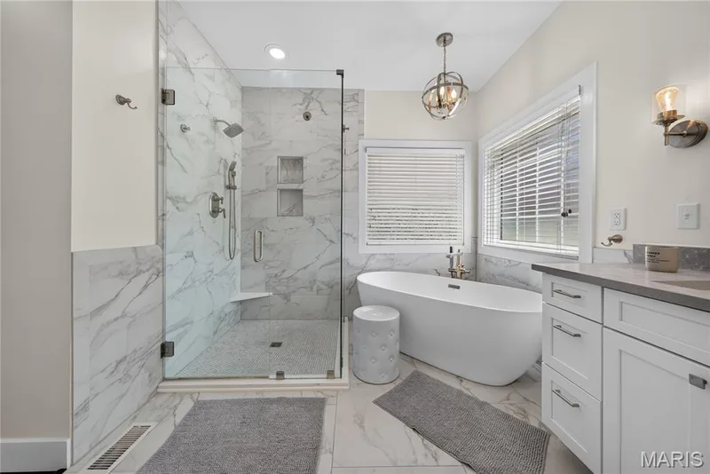 Freestanding soaking tub, glass-enclosed shower with built-in bench, dual shower heads, shelving, and a double vanity — 713 High Point Drive, Lake St. Louis, MO 63367