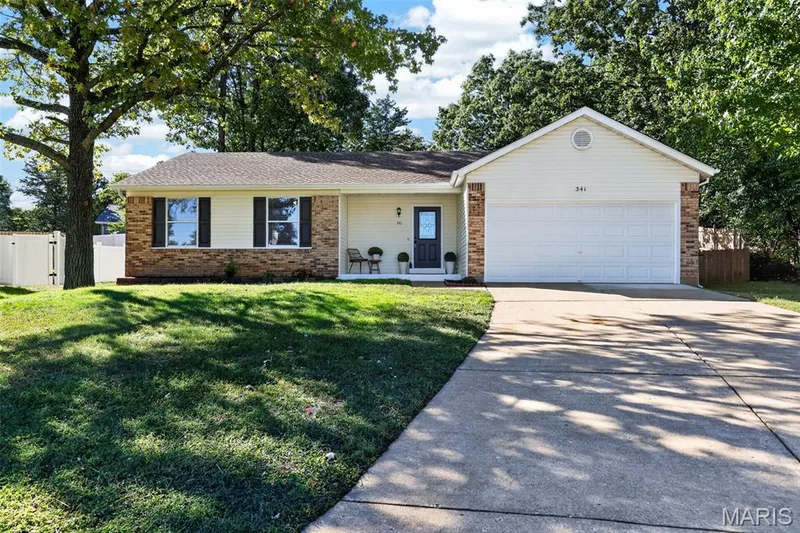 Ranch-style exterior with brick and siding, featuring a two-car garage, concrete driveway, and front entry — 341 Westbrook Drive, O'Fallon, MO 63366