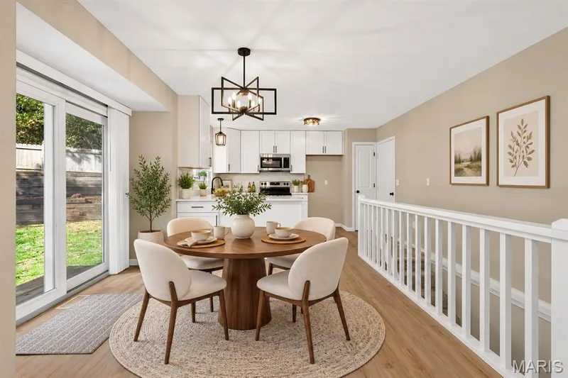Kitchen and dining area featuring white cabinetry, stainless steel appliances, wood-finish flooring, and a sliding glass door to the exterior — 341 Westbrook Drive, O'Fallon, MO 63366