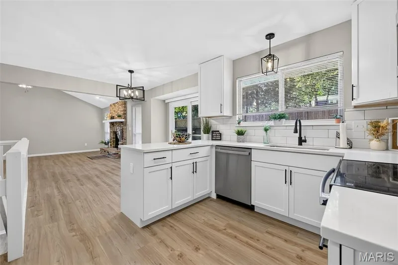 Kitchen featuring white cabinetry, stainless steel appliances, a white subway tile backsplash, and wood-finish flooring — 341 Westbrook Drive, O'Fallon, MO 63366