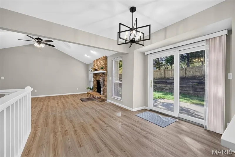 Vaulted ceiling, wood-finish flooring, brick fireplace with mantel, ceiling fan, and sliding glass door to exterior — 341 Westbrook Drive, O'Fallon, MO 63366