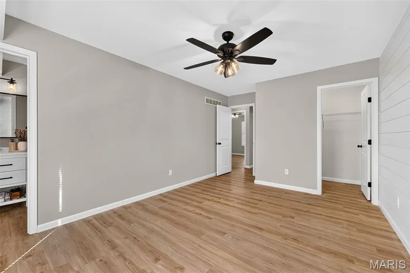 Wood-finish flooring, neutral wall tones, ceiling fan with integrated lighting, white trim, and white paneled doors — 341 Westbrook Drive, O'Fallon, MO 63366