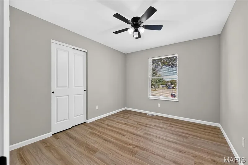 Neutral wall color, wood-finish flooring, white trim, sliding closet doors, and a ceiling fan with light fixture — 341 Westbrook Drive, O'Fallon, MO 63366