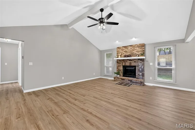 Vaulted ceiling with exposed beams, wood-finish flooring, brick-surround fireplace with mantel, and ceiling fan — 341 Westbrook Drive, O'Fallon, MO 63366