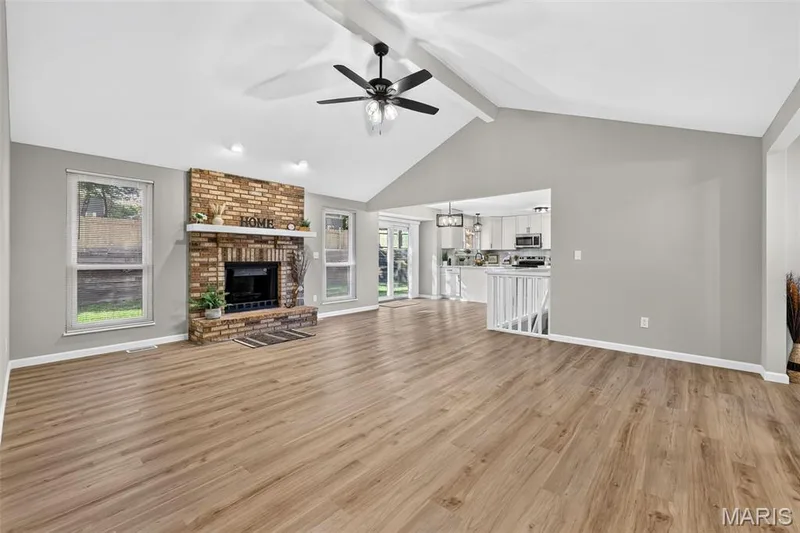 Vaulted ceiling with a ceiling fan, brick fireplace with a mantel, wood-finish flooring, and white painted railings — 341 Westbrook Drive, O'Fallon, MO 63366