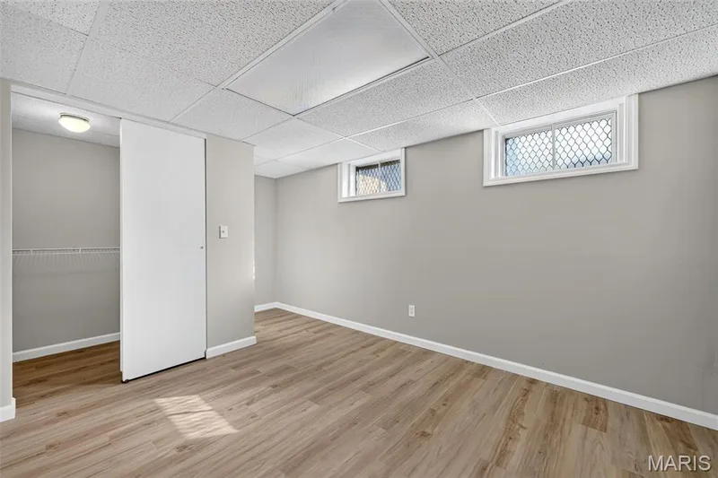 Drop ceiling, wood-finish flooring, light gray wall paint, sliding closet doors, and window screens — 341 Westbrook Drive, O'Fallon, MO 63366