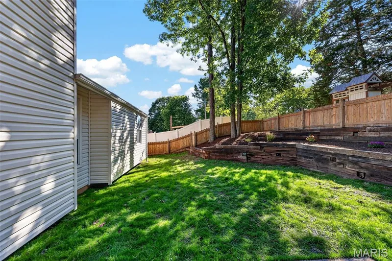 Spacious backyard with lush, level lawn and mature tree canopy providing natural shade — 341 Westbrook Drive, O'Fallon, MO 63366