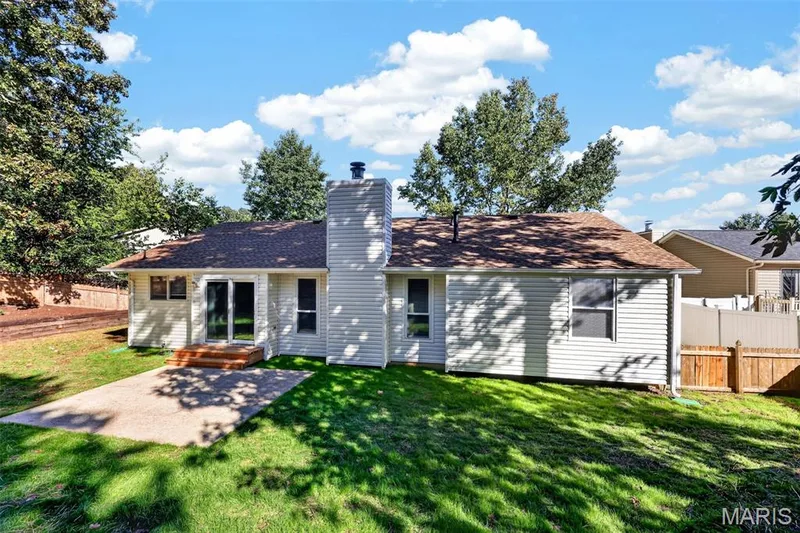 Expansive backyard featuring a concrete patio, a wooden deck, and a privacy fence — 341 Westbrook Drive, O'Fallon, MO 63366
