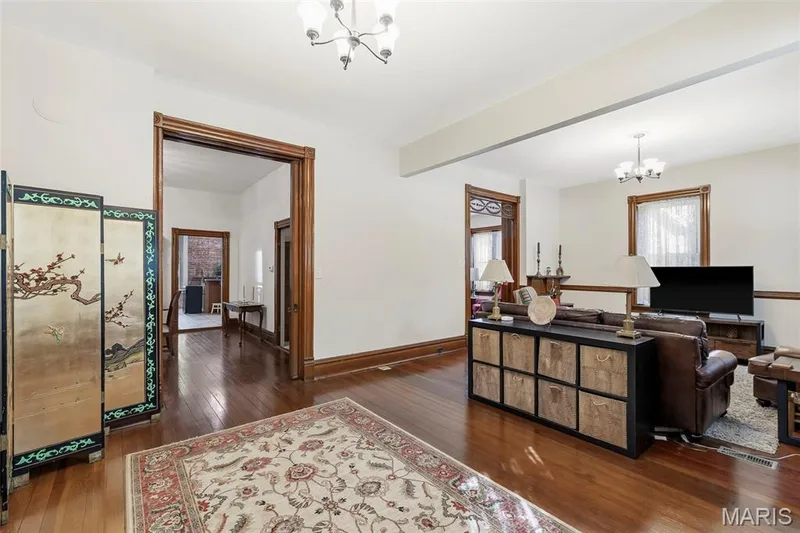 Interior space featuring dark wood-finish flooring, high ceilings, custom wood door casing, multi-pane transom window details, and multi-arm chandelier lighting — 711 N 5th Street, St Charles, MO 63301