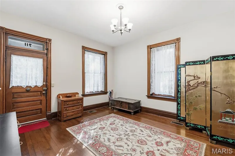 Entry featuring a solid wood door with decorative glass transom, original wood trim, wood-finish flooring, and a multi-arm metal chandelier — 711 N 5th Street, St Charles, MO 63301