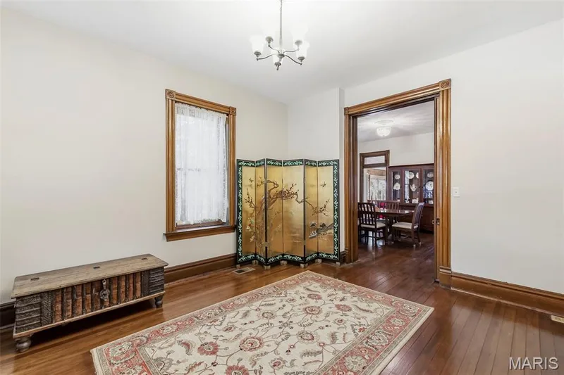 Natural wood-finish flooring, intricate natural wood door casing, classic natural wood window trim, and a decorative multi-arm ceiling light fixture — 711 N 5th Street, St Charles, MO 63301