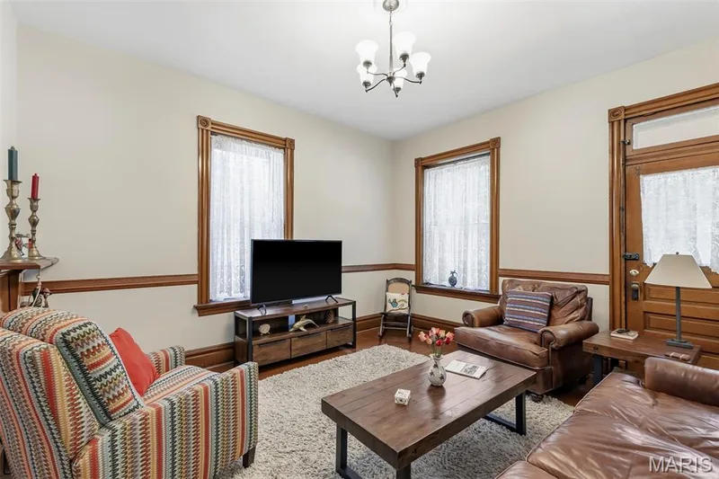 Interior space featuring natural wood-finish door and window trim, chair rail molding, multi-paneled wood entrance door, and a multi-arm chandelier — 711 N 5th Street, St Charles, MO 63301