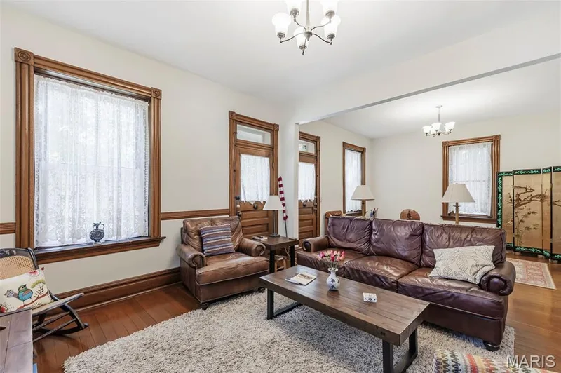 Interior space featuring original natural wood trim, wainscoting, hardwood flooring, multi-paneled wood doors, and multi-light ceiling fixtures — 711 N 5th Street, St Charles, MO 63301