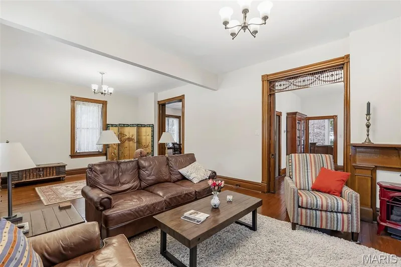 Interior space featuring natural wood-finish flooring, ornate wood door casing with decorative lattice trim, and wood-mantel fireplace — 711 N 5th Street, St Charles, MO 63301