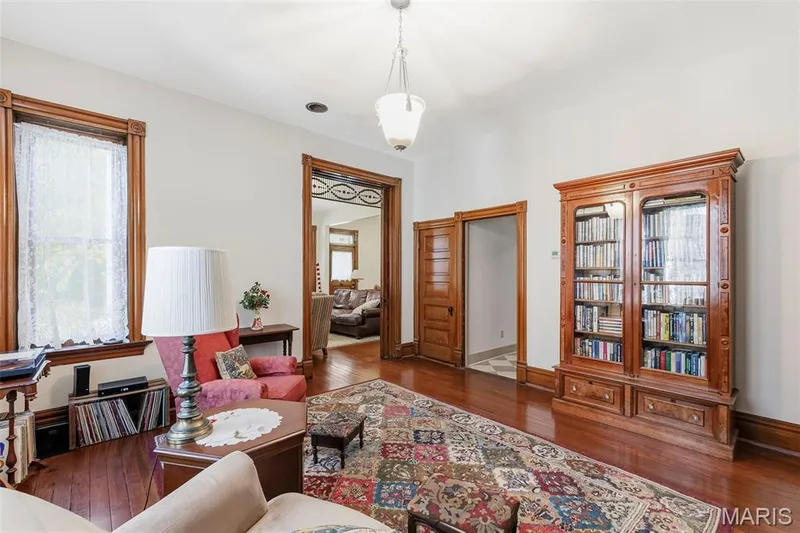 Interior space featuring wood-finish flooring, original stained wood door casings and trim, an ornate glass-paneled transom over the entryway, and a hanging pendant light fixture — 711 N 5th Street, St Charles, MO 63301