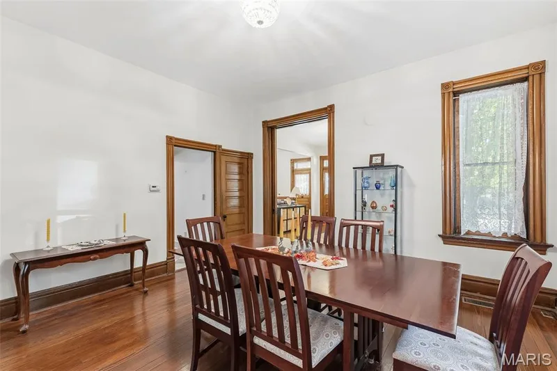 Dining area featuring hardwood flooring, natural wood door and window casing, solid wood five-panel door, and a multi-pane window — 711 N 5th Street, St Charles, MO 63301