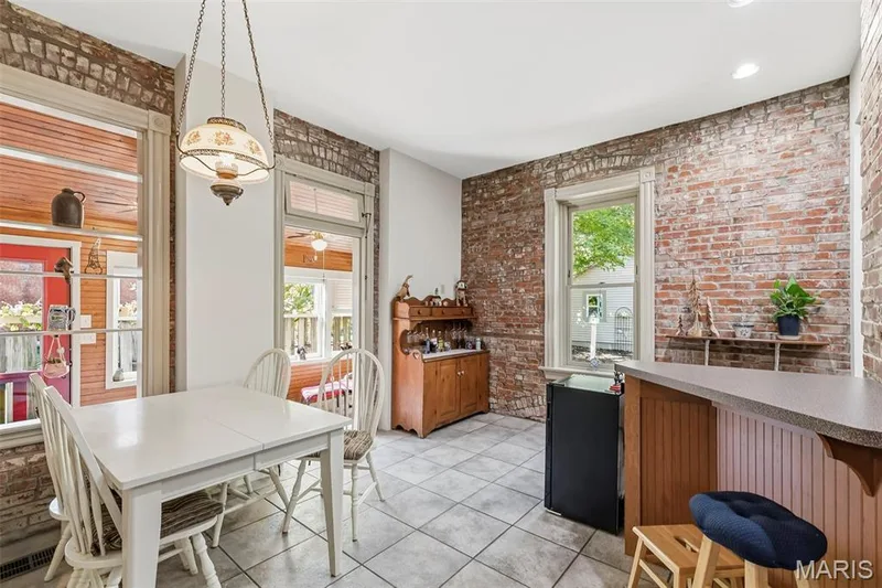 Exposed brick walls, tile flooring, built-in wooden cabinetry, a breakfast bar with beadboard detailing, and a hanging pendant light fixture — 711 N 5th Street, St Charles, MO 63301