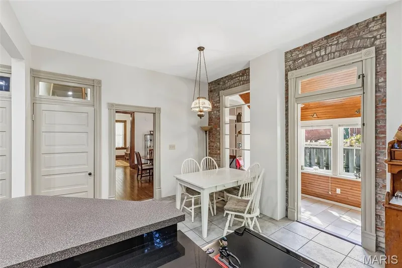 Exposed brick wall accents, decorative arched door headers, transom window detailing, beadboard ceiling accents in the sunroom, and tile flooring — 711 N 5th Street, St Charles, MO 63301