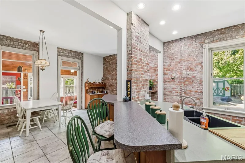 Exposed brick walls, tile flooring, breakfast bar with solid-surface countertop, recessed ceiling lighting, and windows featuring decorative woodwork trim — 711 N 5th Street, St Charles, MO 63301