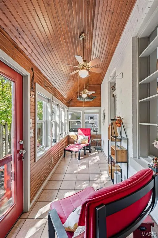 Sunroom featuring wood-paneled walls and ceiling, ceramic tile flooring, built-in shelving, and dual ceiling fans — 711 N 5th Street, St Charles, MO 63301