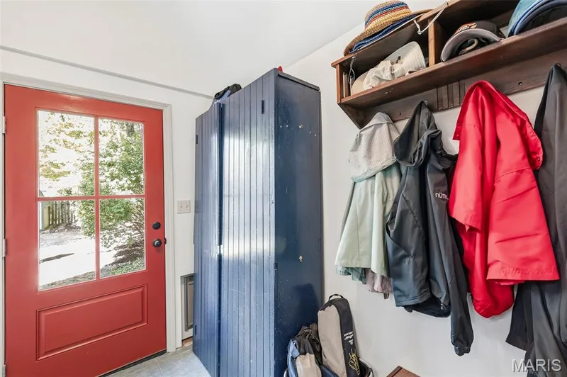 Exterior door with multi-pane glass inlay, vertical-paneled built-in cabinetry, and wall-mounted wooden shelf with integrated garment hooks — 711 N 5th Street, St Charles, MO 63301