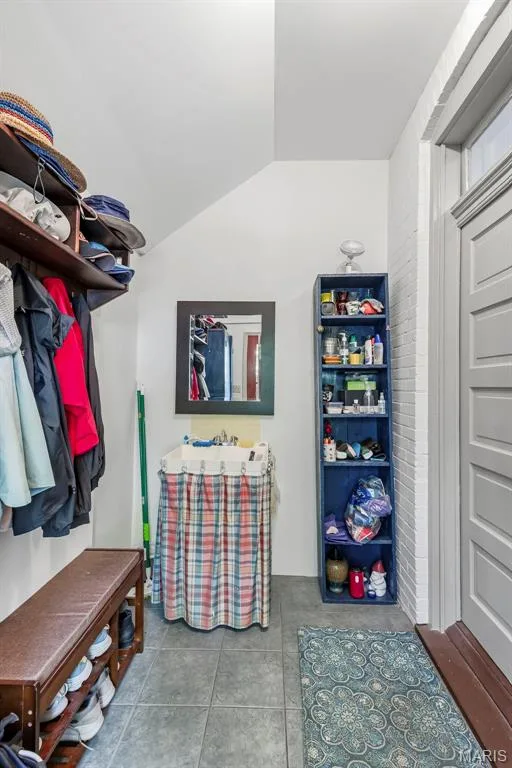 Ceramic tile flooring, white brick accent wall, wall-mounted mirror, and fixed shelving unit — 711 N 5th Street, St Charles, MO 63301