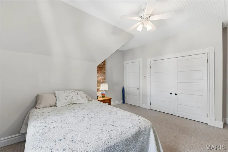 Exposed brick architectural element, tongue-and-groove beadboard ceiling, white five-panel interior doors, and a central white ceiling fan with integrated lighting — 711 N 5th Street, St Charles, MO 63301