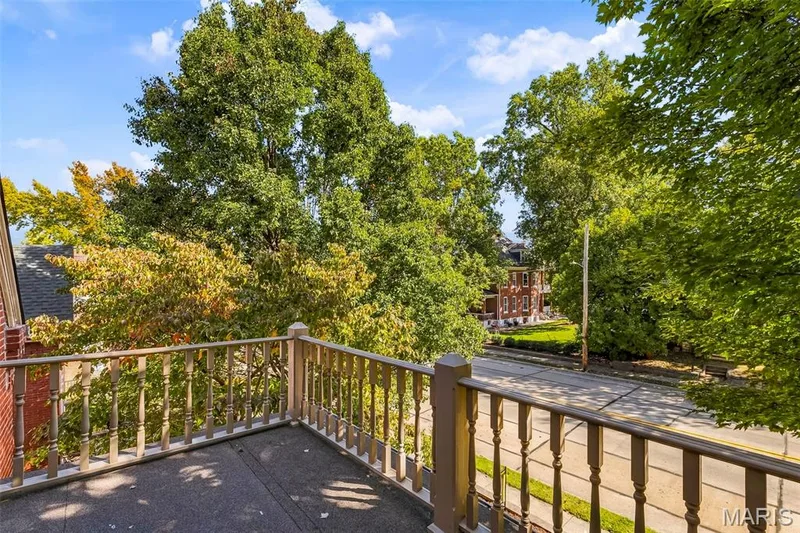 Balcony with painted wood balustrades and textured concrete flooring — 711 N 5th Street, St Charles, MO 63301