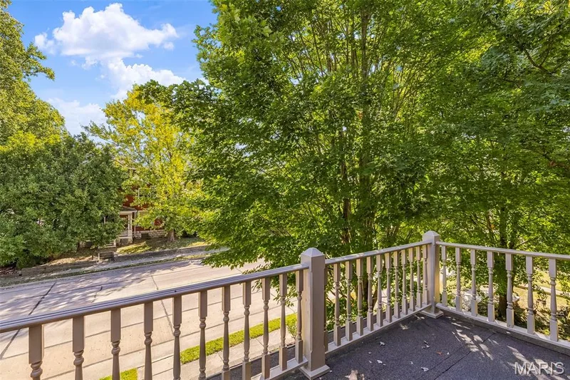 Baalcony featuring painted wood-spindle railings and mature canopy trees — 711 N 5th Street, St Charles, MO 63301