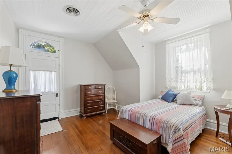 Wood-finish flooring, beadboard ceiling, ceiling fan with integrated lighting, and an exterior door with an arched transom window — 711 N 5th Street, St Charles, MO 63301